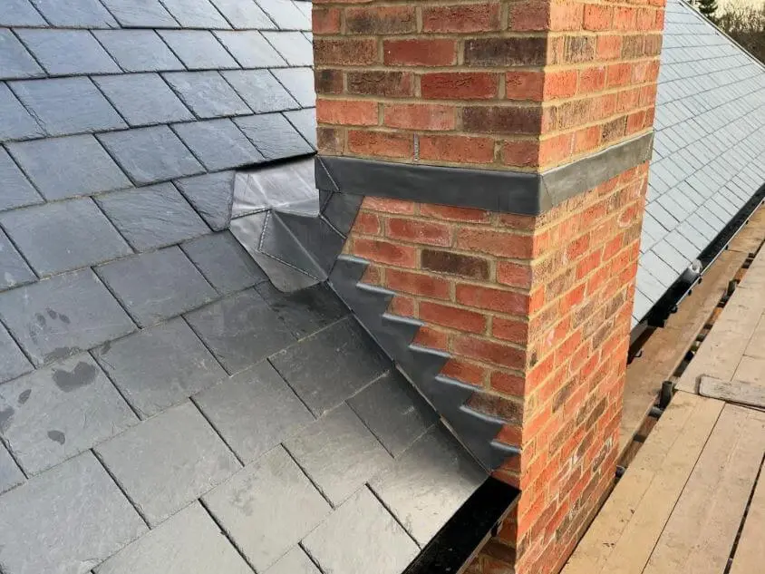 Lead flashing around a brick chimney on a slate roof