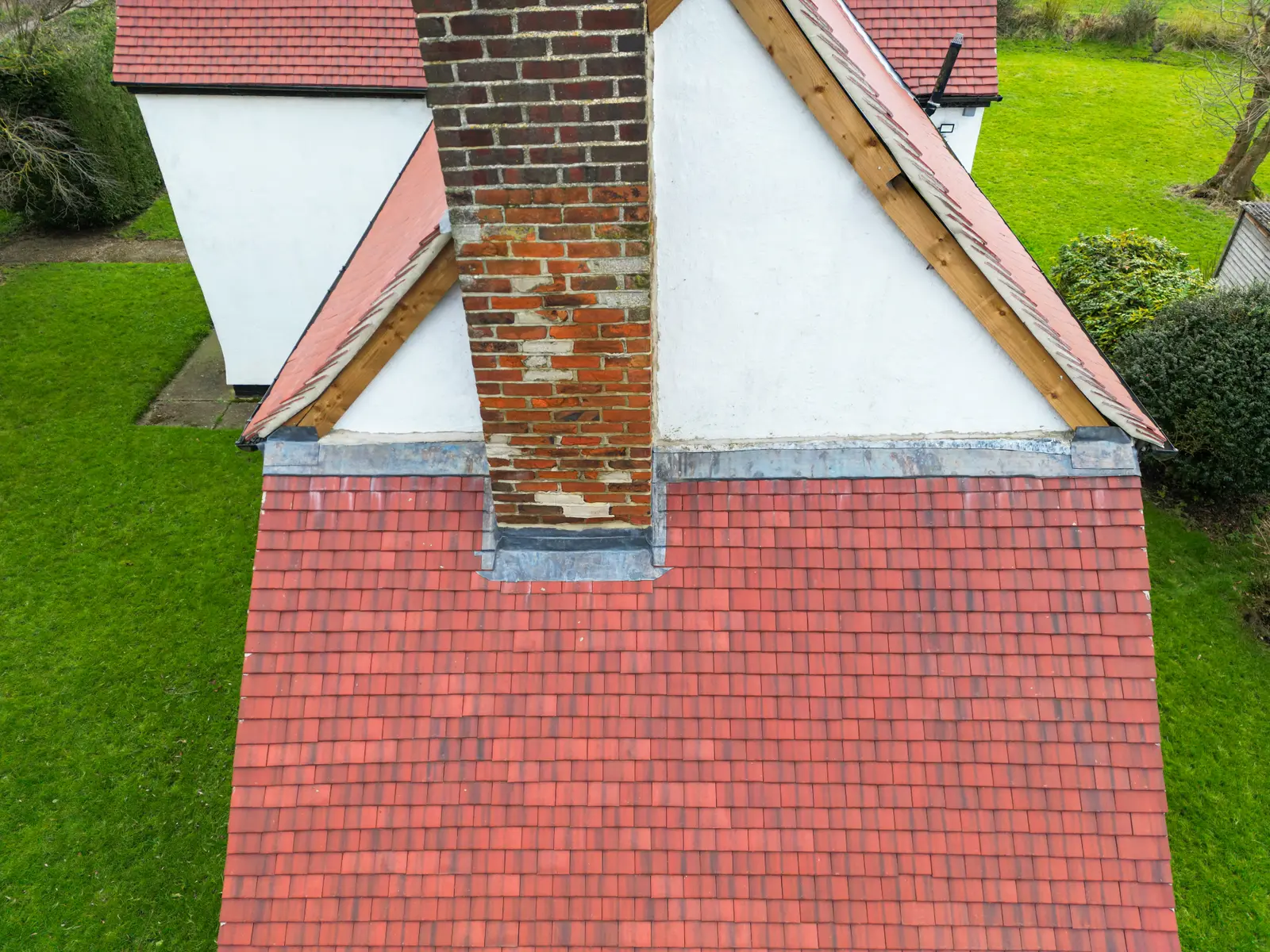 Aerial view of a brick chimney with lead flashing on a tiled roof