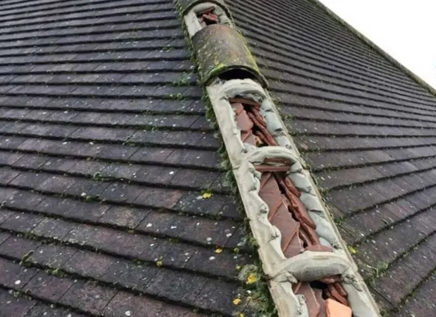 Broken ridge tiles and failed mortar on a tiled roof