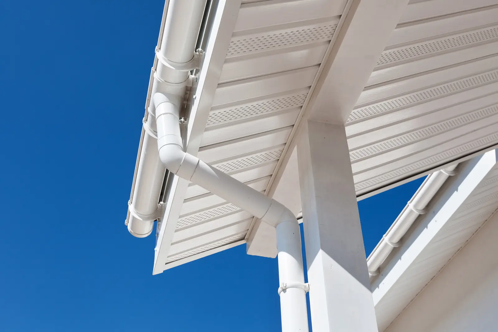 White uPVC soffits and downpipe against a blue sky