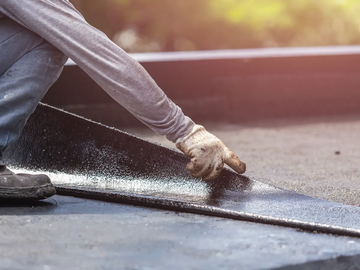 Roofer pressing down a new felt membrane on a flat roof