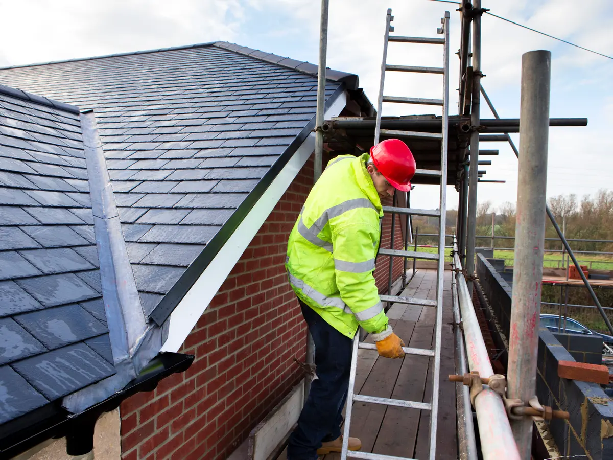 Roofer on the scaffold beside a slate roof