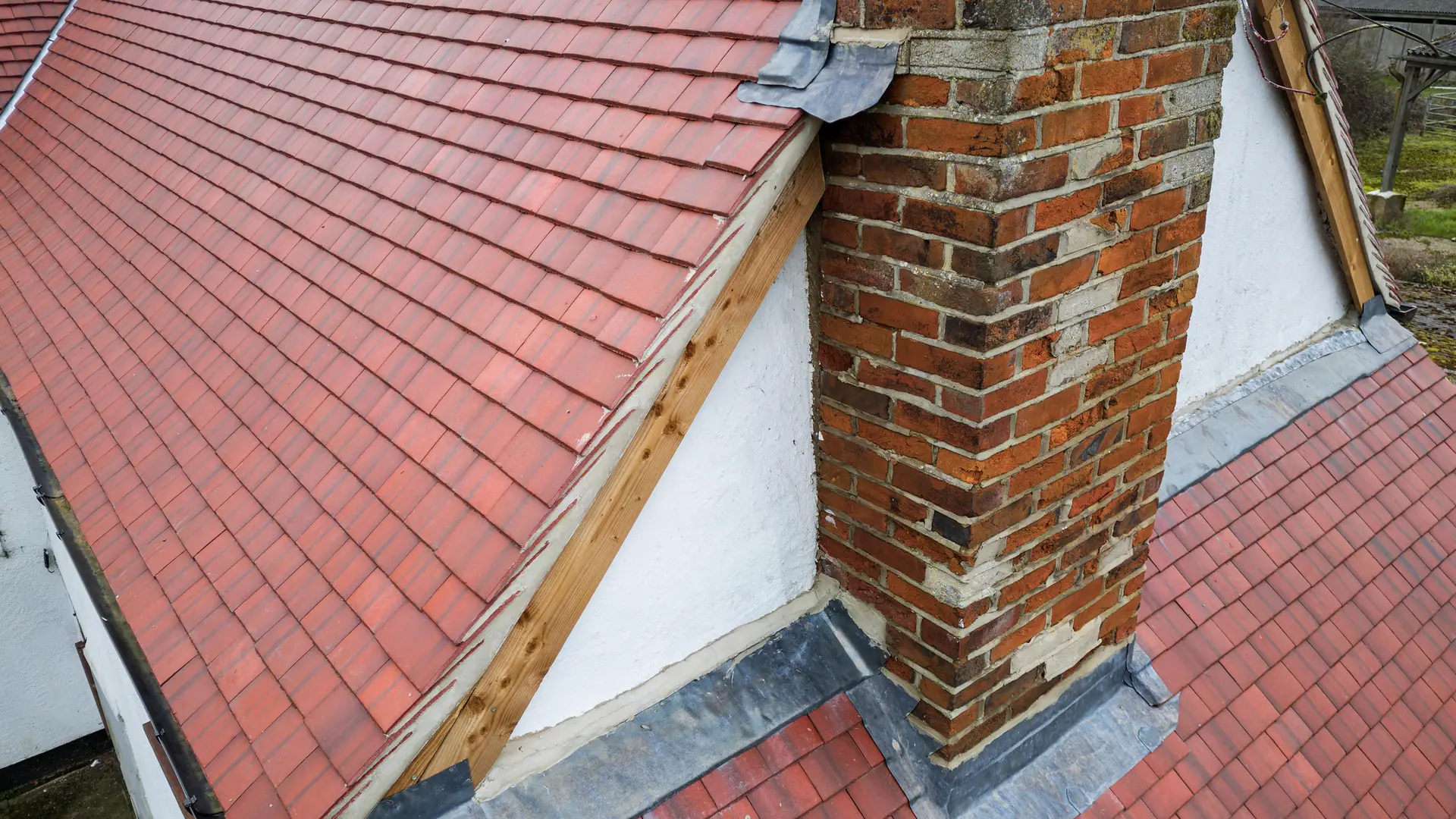 Brick chimney with new lead flashing on a plain tiled roof