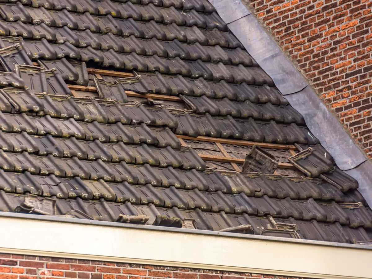 Storm-damaged pitched roof with missing and slipped tiles