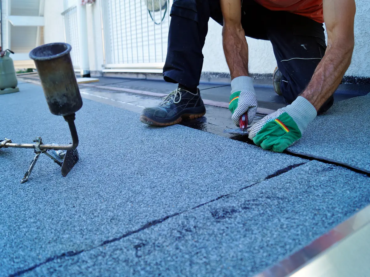 Roofer sealing the seams of mineral felt on a flat roof