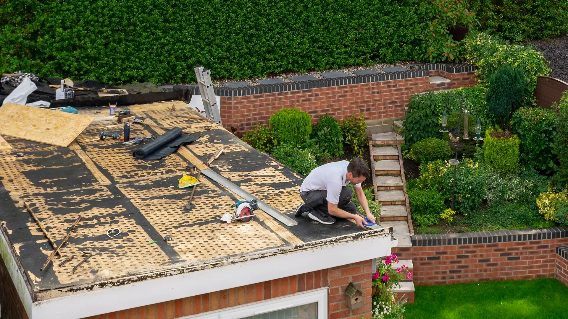 Roofer re-boarding a flat roof on a house extension