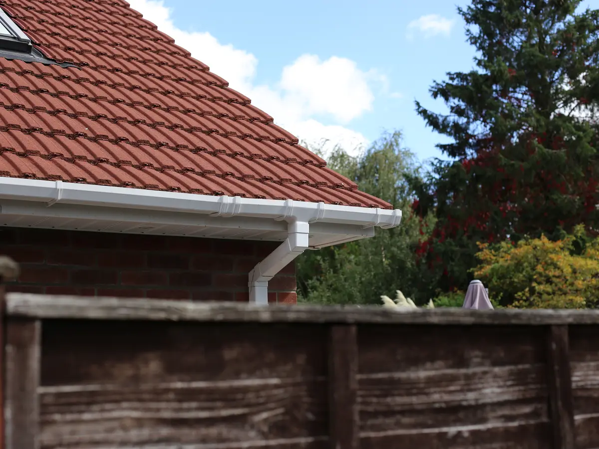 White gutter and downpipe below a red tiled roof