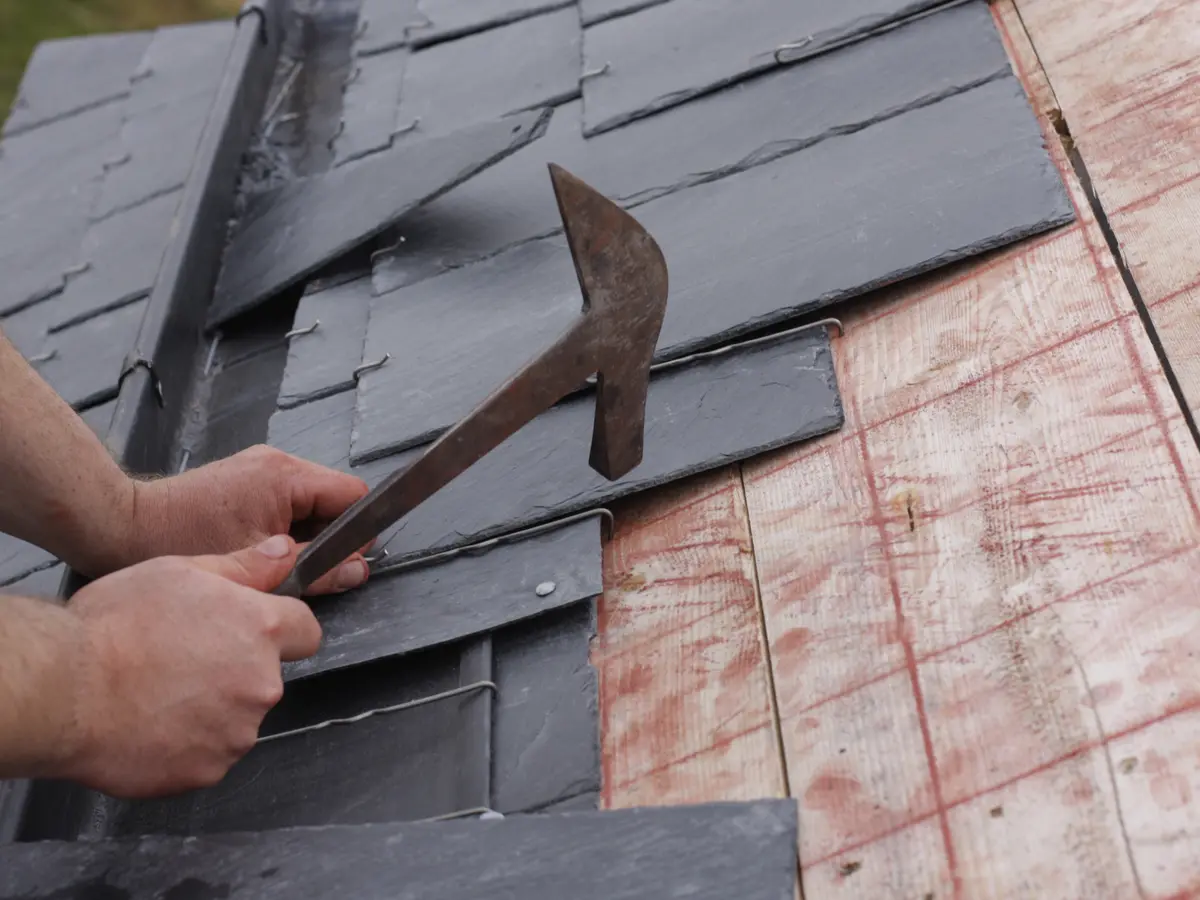 Roofer fixing natural slates with a slate hammer